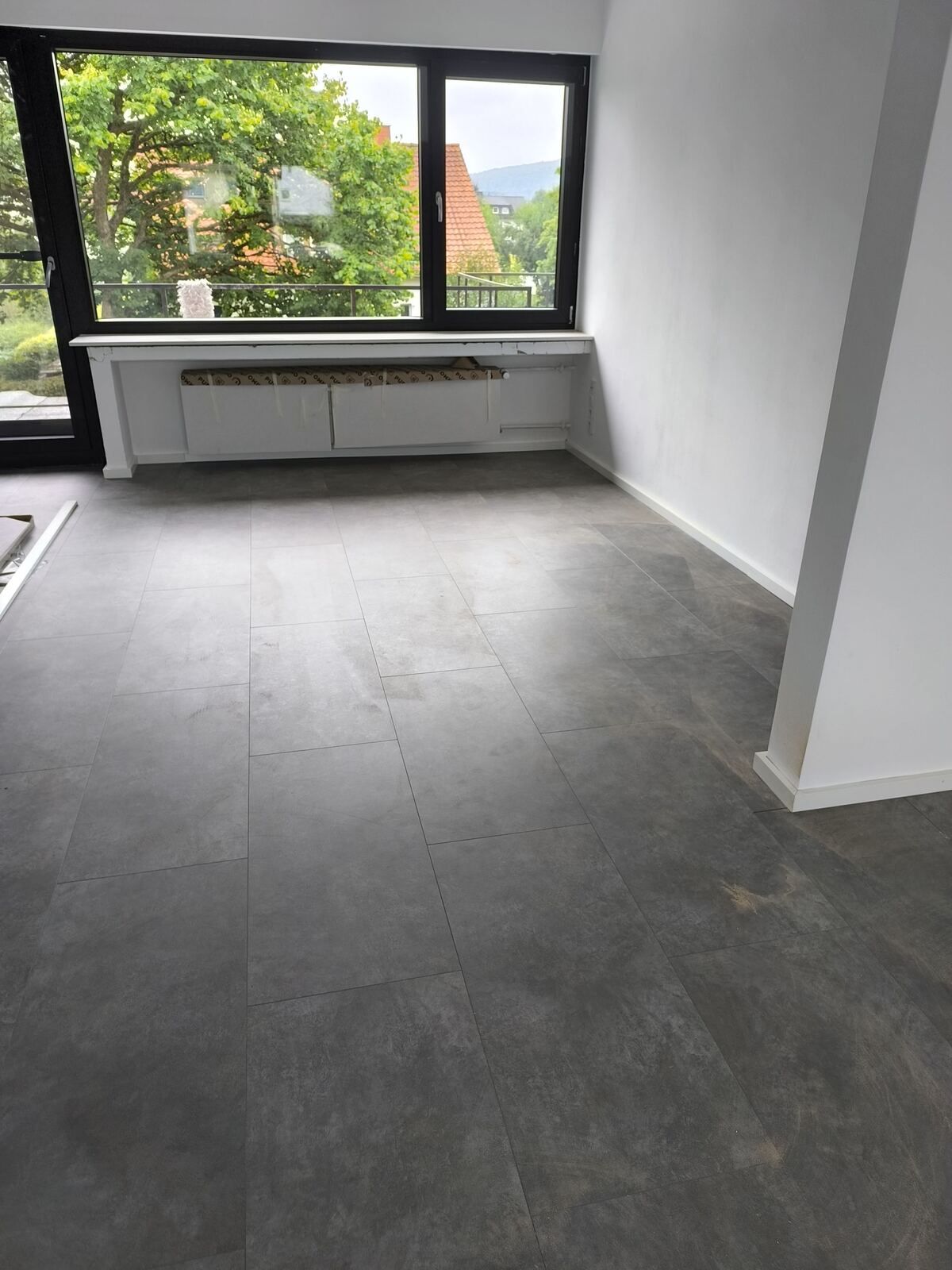 Ein leerer Raum mit einem großen Fenster und einem grauen Boden
