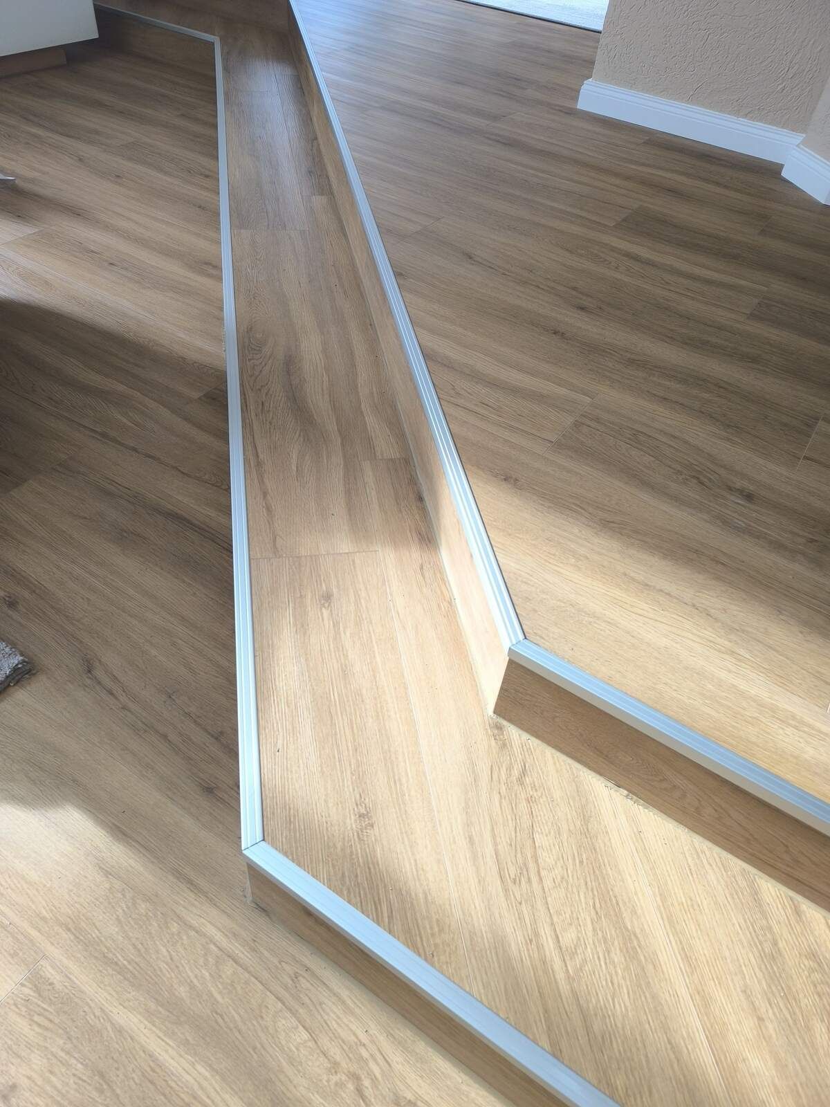 Eine Nahaufnahme eines Holzbodens mit Treppe in einem Raum.