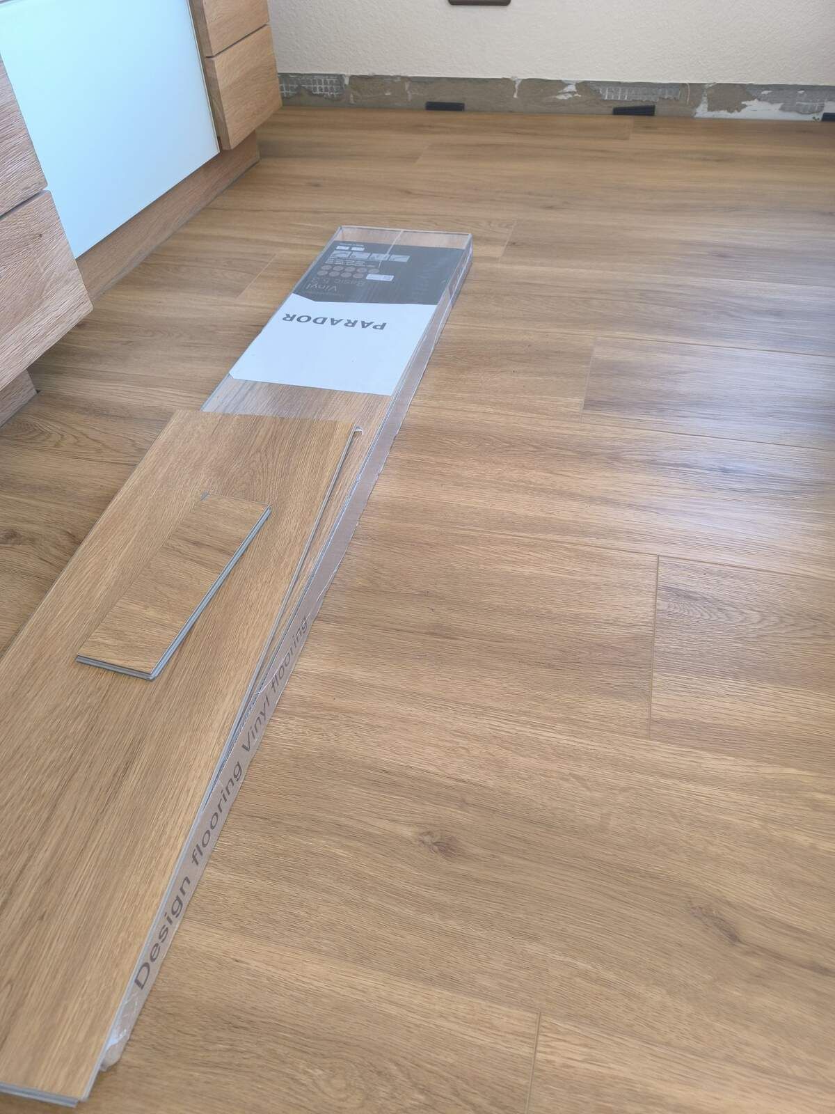 In einer Küche liegt ein Stück Holz auf dem Boden.