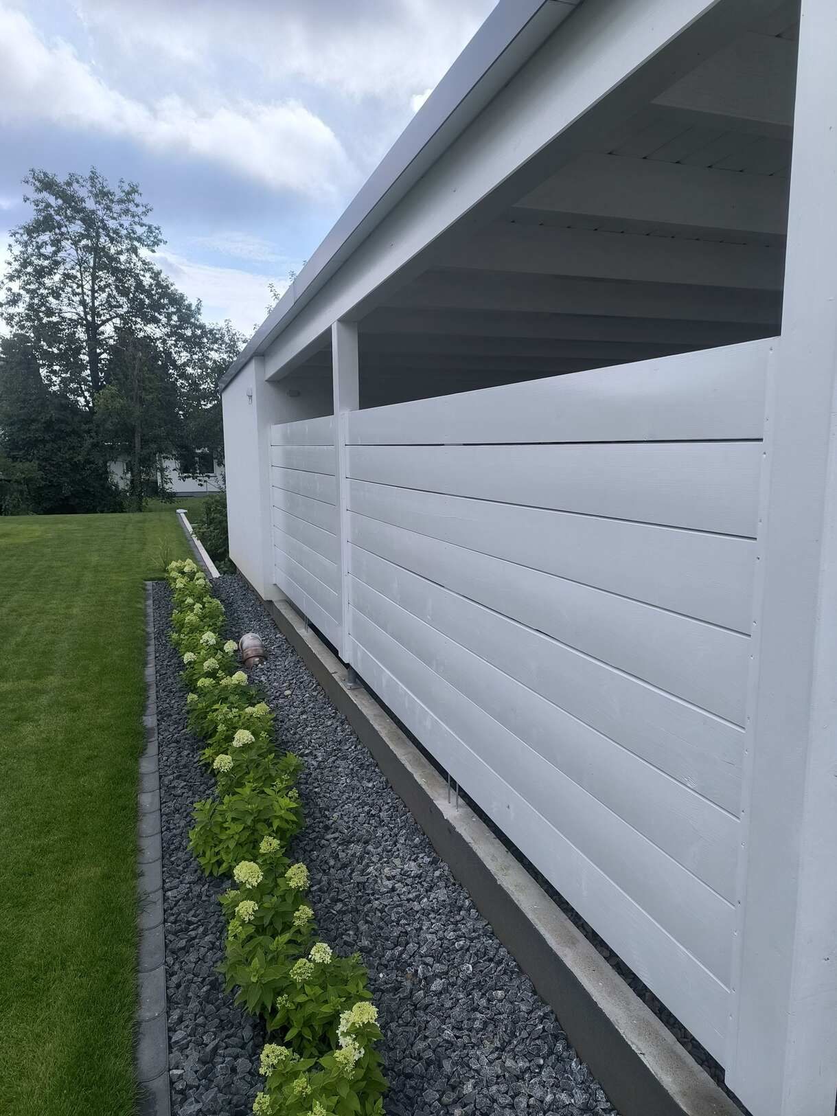 Ein weißes Gebäude mit einem Zaun und Blumen davor