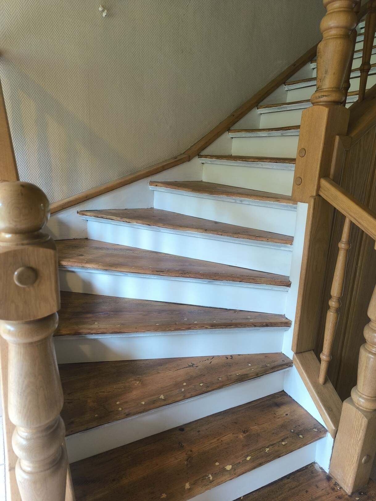 Eine Holztreppe mit weißen Stufen und einem Holzgeländer.