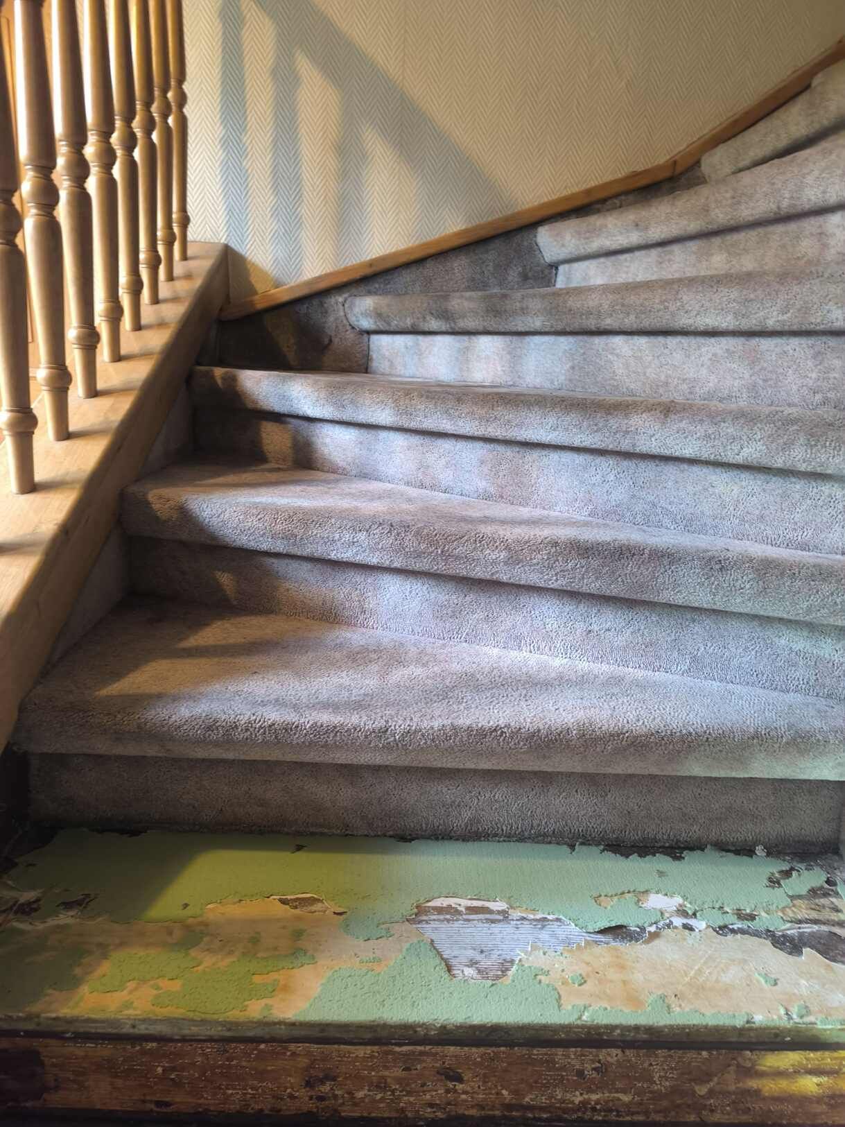 Eine Nahaufnahme einer Treppe mit einem Holzgeländer.