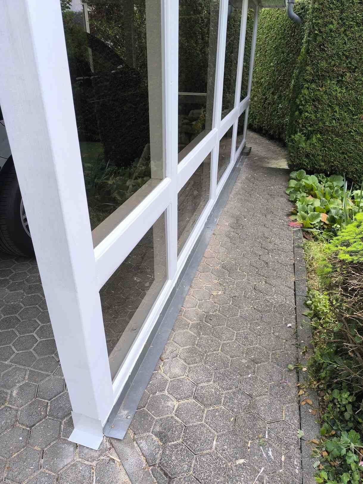 Ein weißes Gebäude mit vielen Fenstern steht neben einem Bürgersteig.