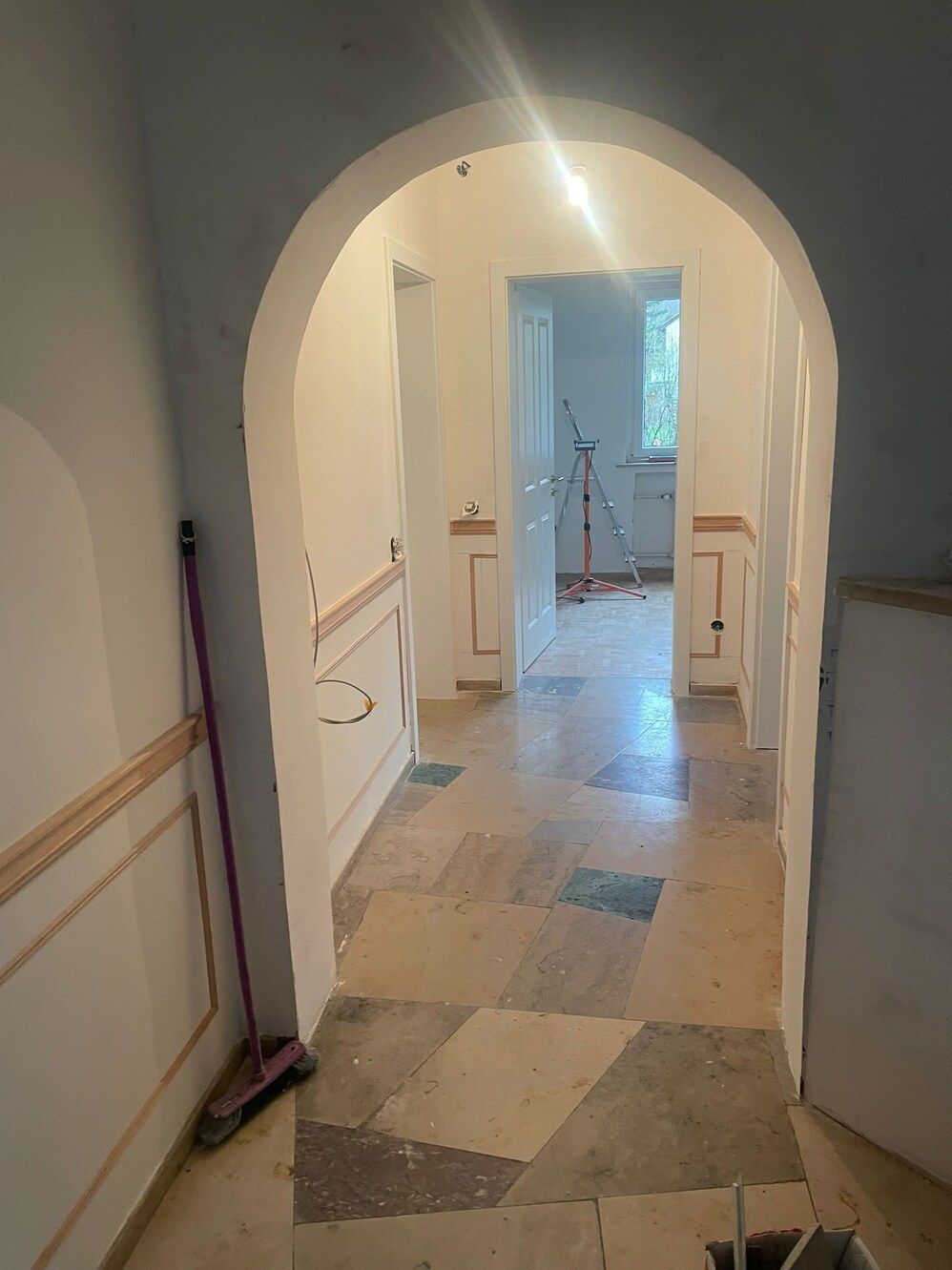 Ein Flur mit Bögen und einem Besen auf dem Boden