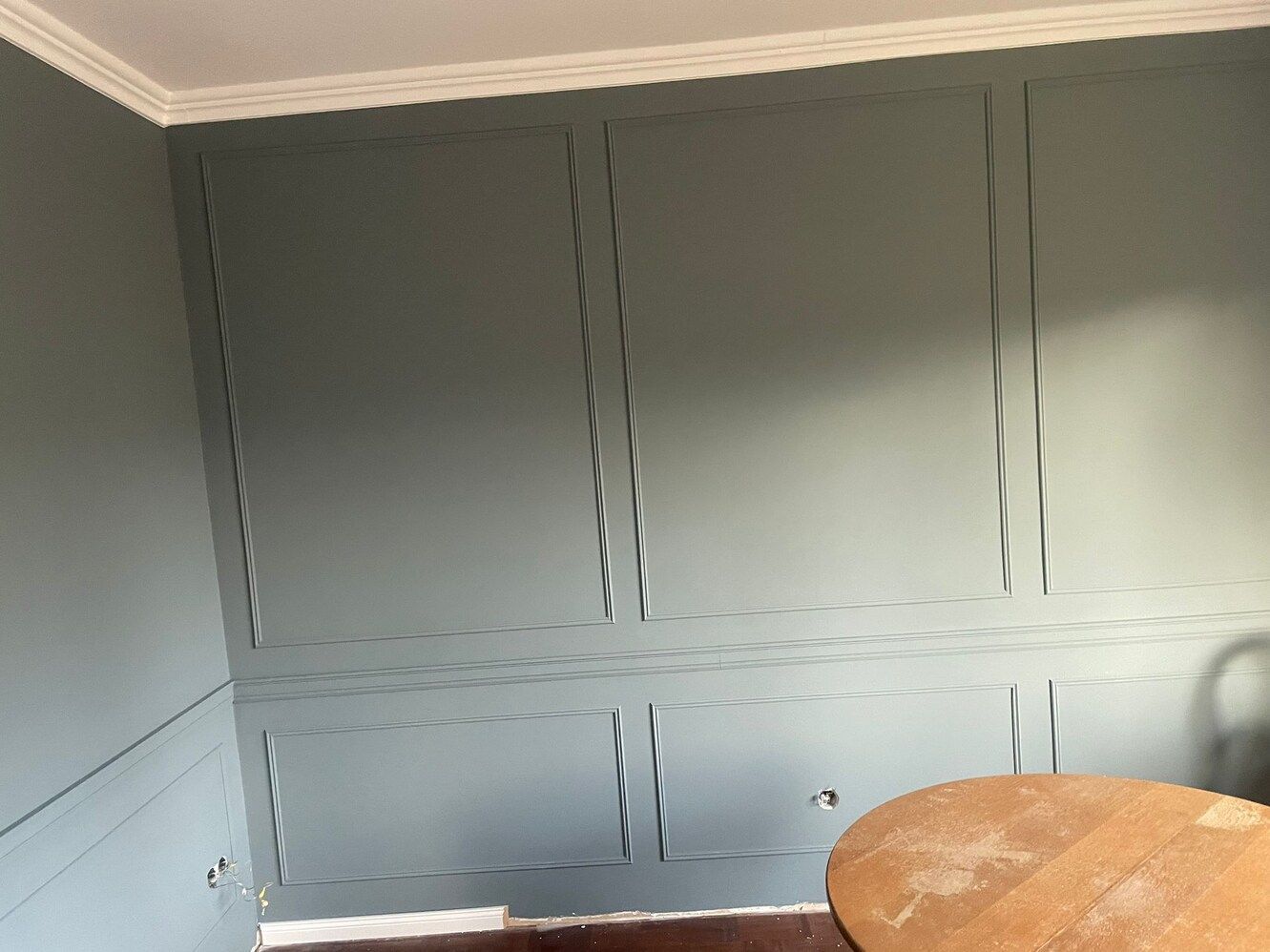 Ein Raum mit einer grauen Wand und einem Holztisch