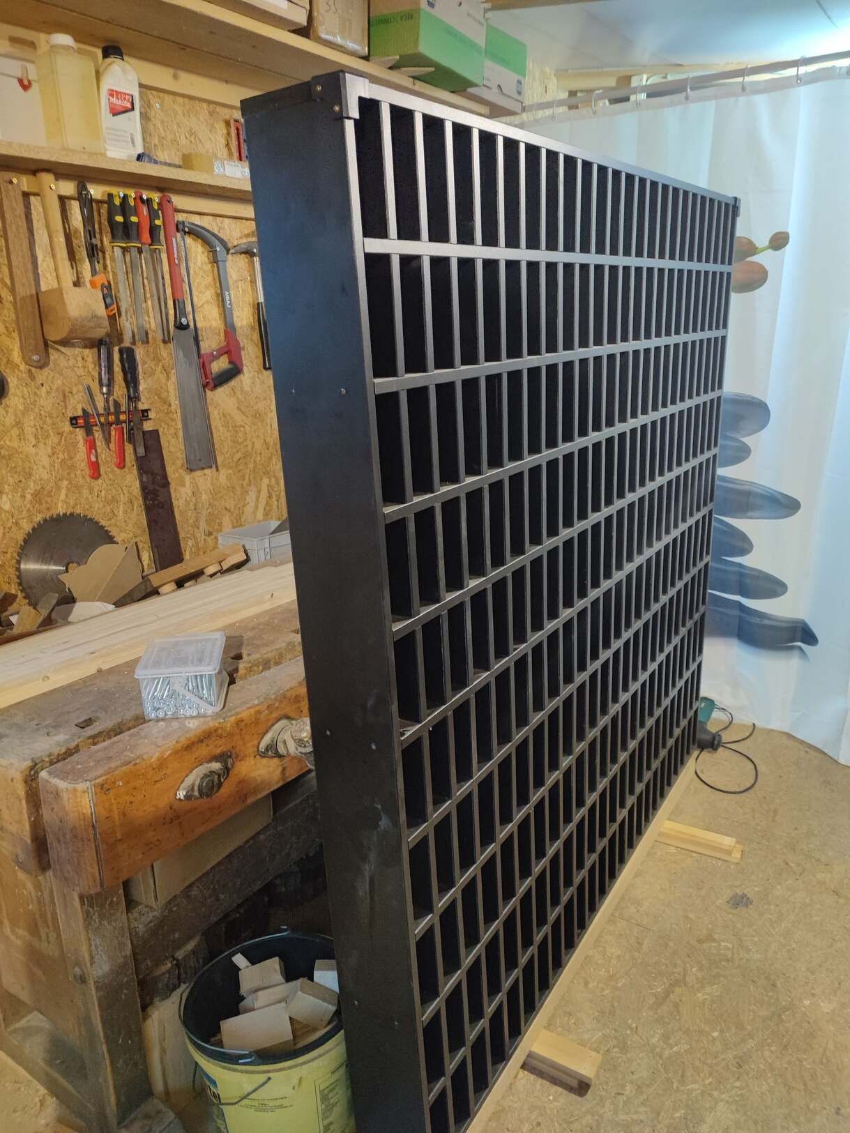 Eine hölzerne Werkbank mit einem Eimer Farbe und einem Regal mit Werkzeugen darauf.