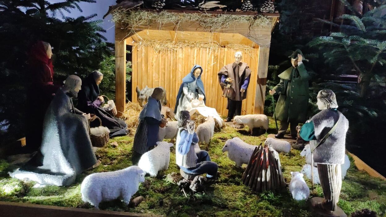 Eine Weihnachtskrippe mit Schafen und Menschen in einem Stall.