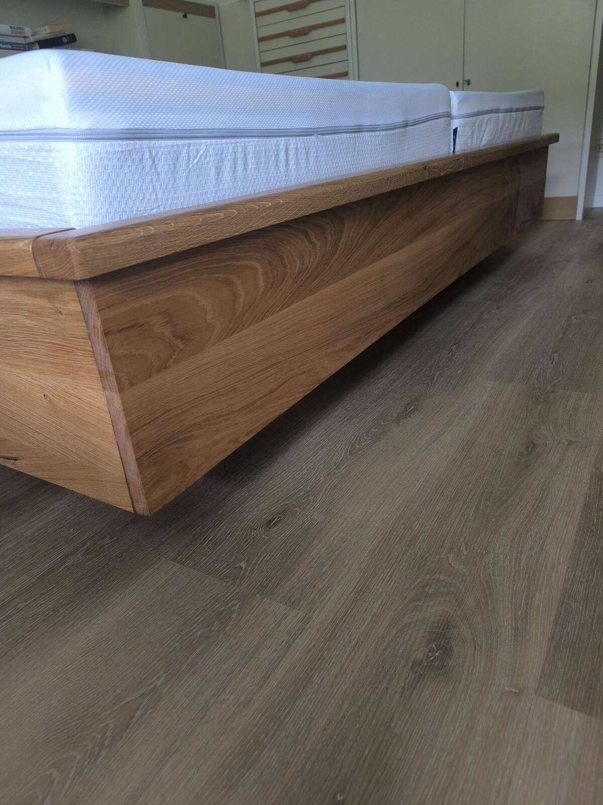 Ein hölzerner Bettrahmen mit einer weißen Matratze darauf.