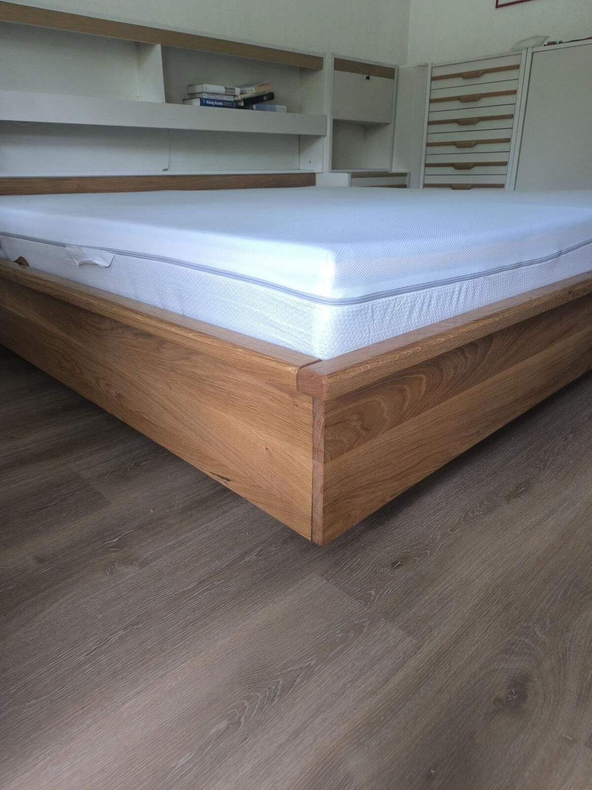 Ein Bett mit Holzrahmen und weißer Matratze in einem Schlafzimmer.