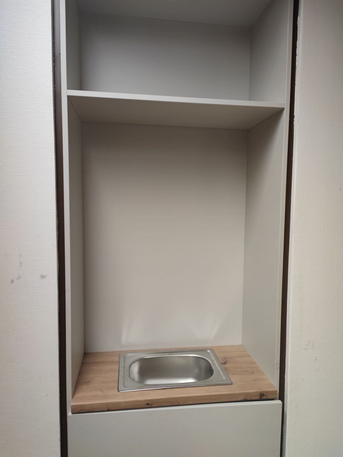 In der Ecke eines Schranks steht ein Waschbecken.