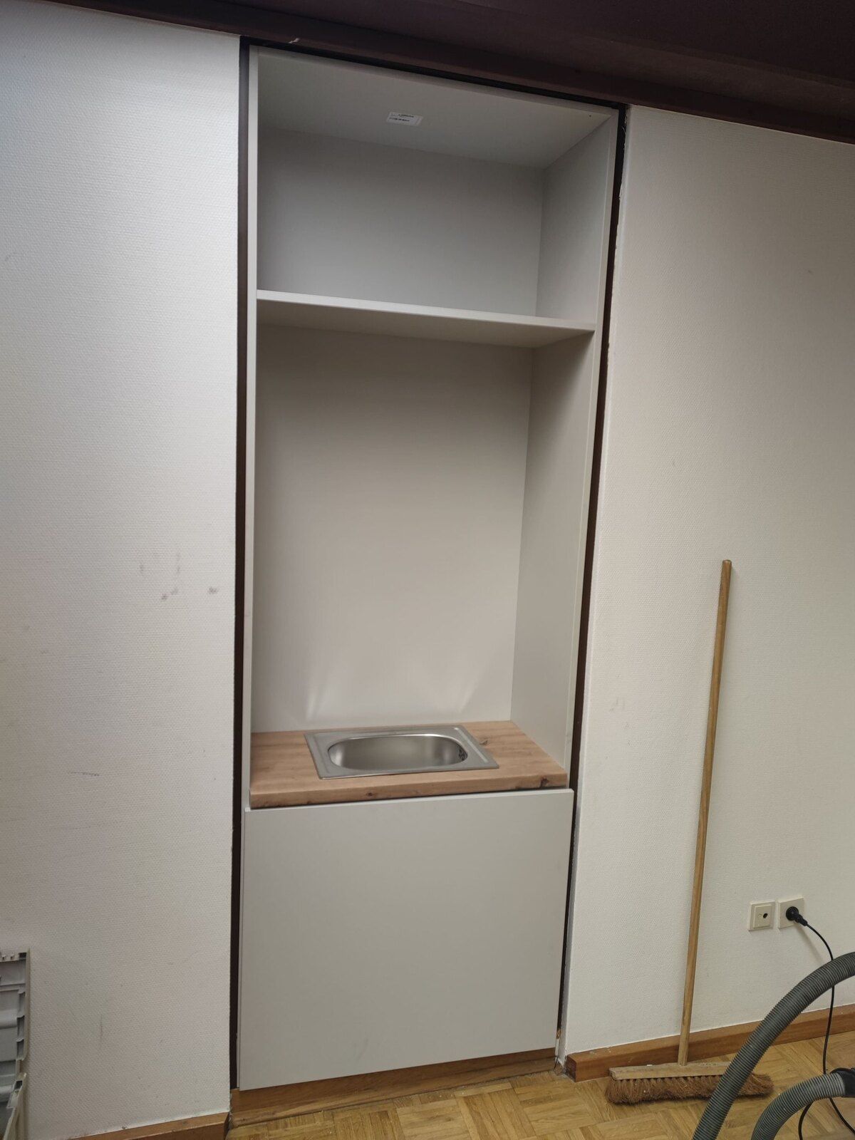 Ein Raum mit einem Waschbecken und einem Besen darin