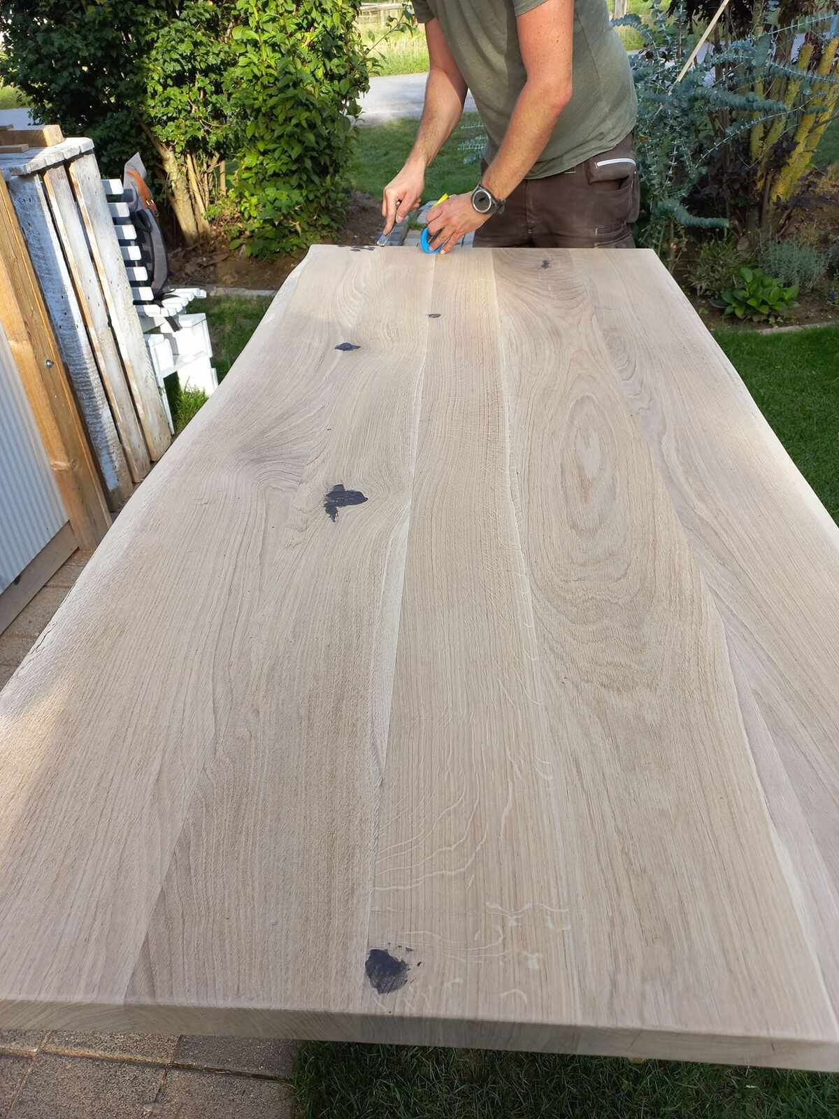 Ein Mann arbeitet draußen an einem Holztisch.