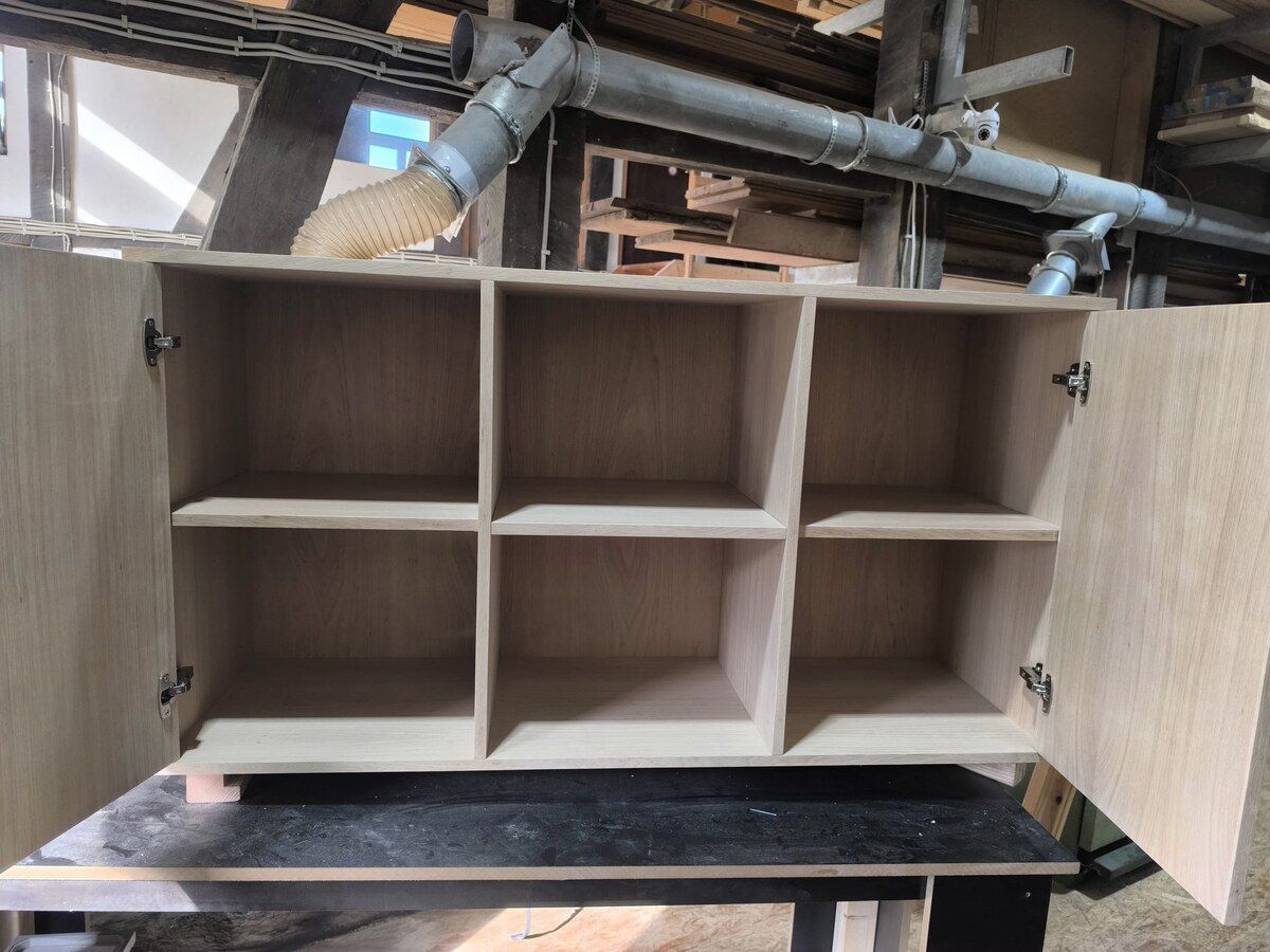 Auf einem Tisch steht ein Holzregal mit offenen Türen.