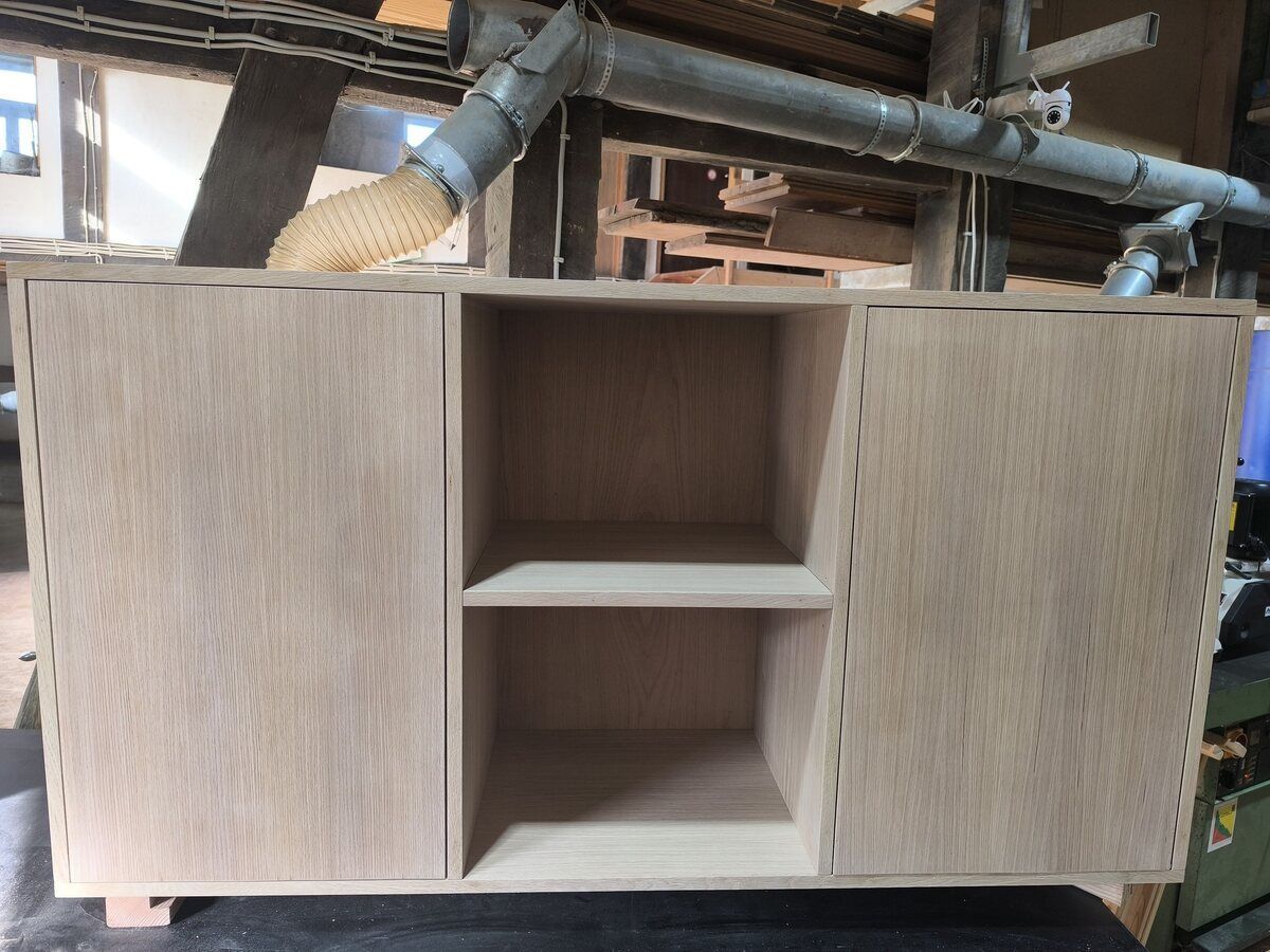 Auf einem Tisch steht ein Holzschrank mit zwei Regalen und zwei Türen.