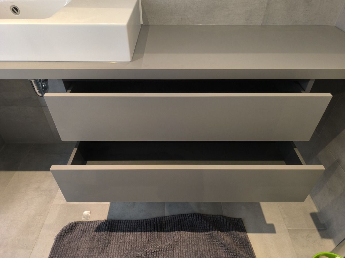 Ein Badezimmerschrank mit offenen Schubladen und einem Waschbecken.