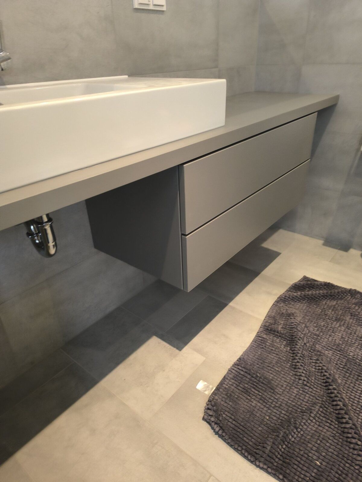 Ein Badezimmer mit Waschbecken und einem Teppich auf dem Boden