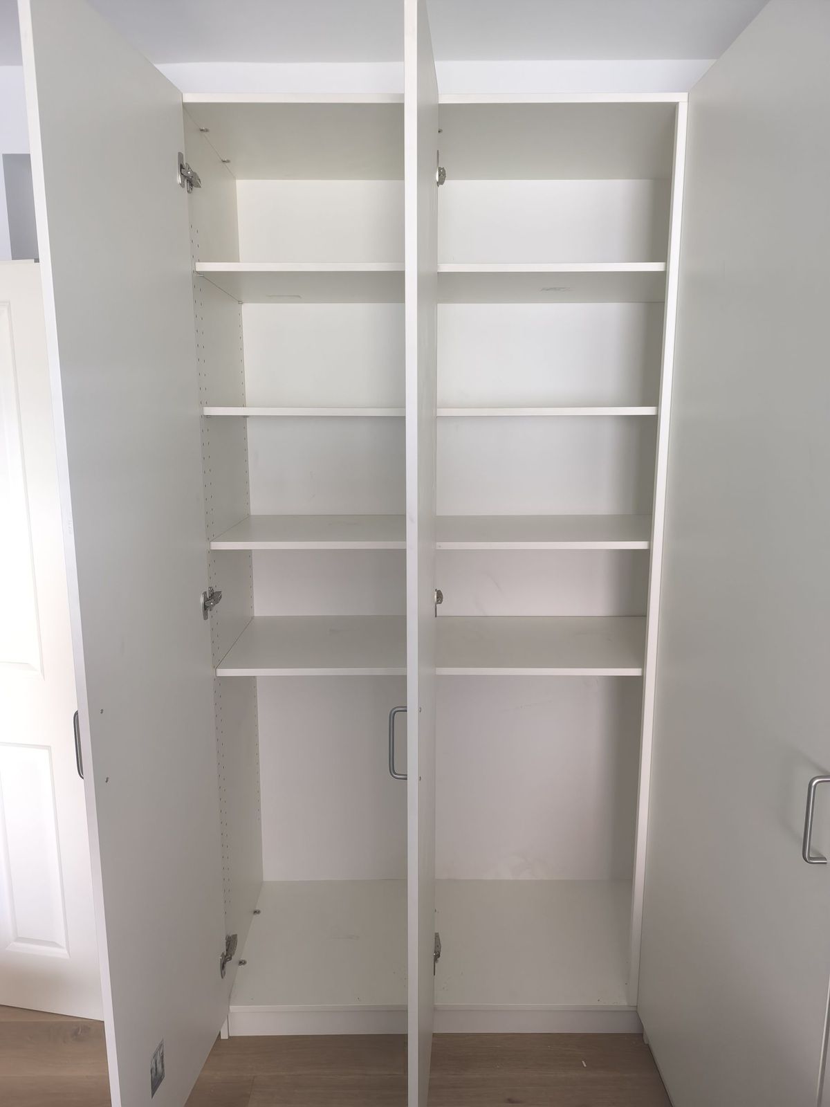 Ein weißer Schrank mit offenen Türen und Regalen.