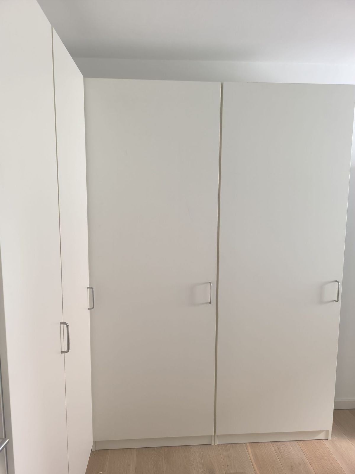 Ein Raum mit vielen weißen Schränken und einem Holzboden.