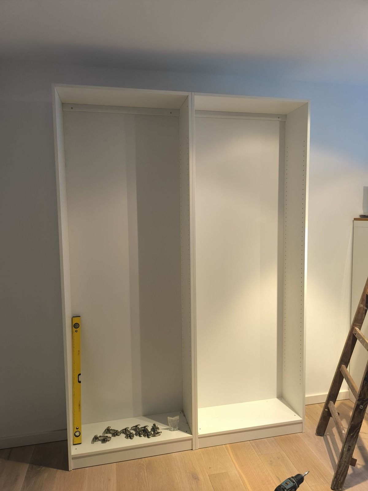 In einem Raum mit einer Leiter wird ein Kleiderschrank eingebaut.