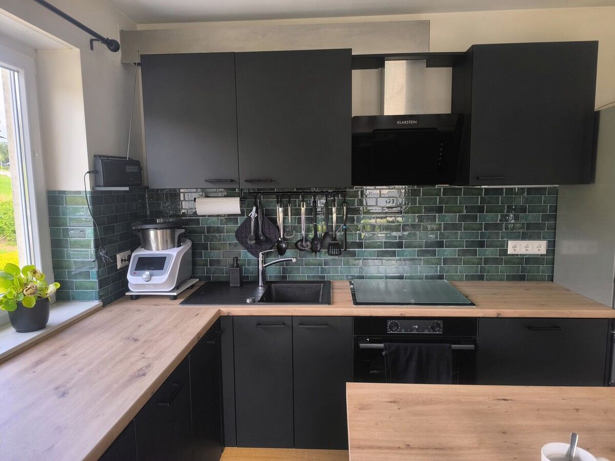 Eine Küche mit schwarzen Schränken und einer Holzarbeitsplatte