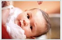 Bebé siendo bañado, mirando a la cámara con ojos dulces.