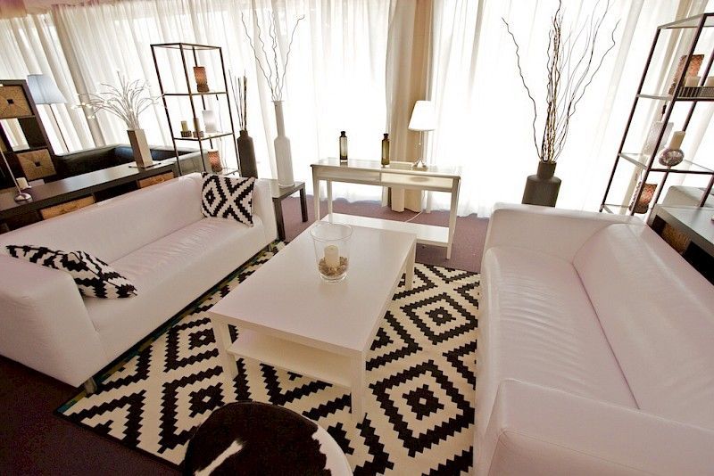 Sofás blancos y mesa de centro en una sala de estar moderna con una alfombra geométrica en blanco y negro.