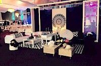 Área de salón con sofás blancos, detalles en blanco y negro y un fondo con diseño de mandala en un evento.