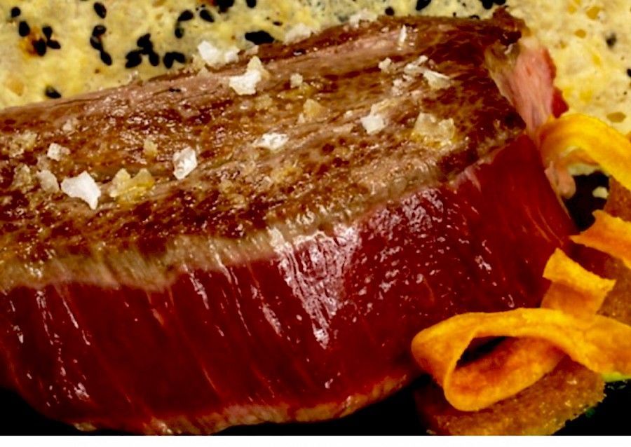 Filete de atún sellado con sal marina, servido con patatas fritas y una galleta de sésamo negro.