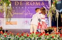 Un niño y una niña vestidos de gala se besan en el escenario con decoraciones florales.