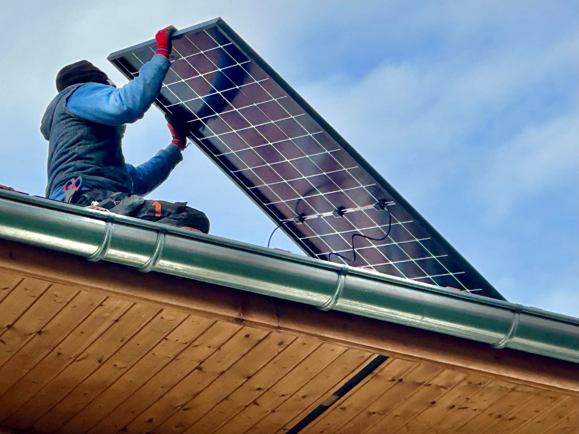 Personne installant un panneau solaire sur un toit.