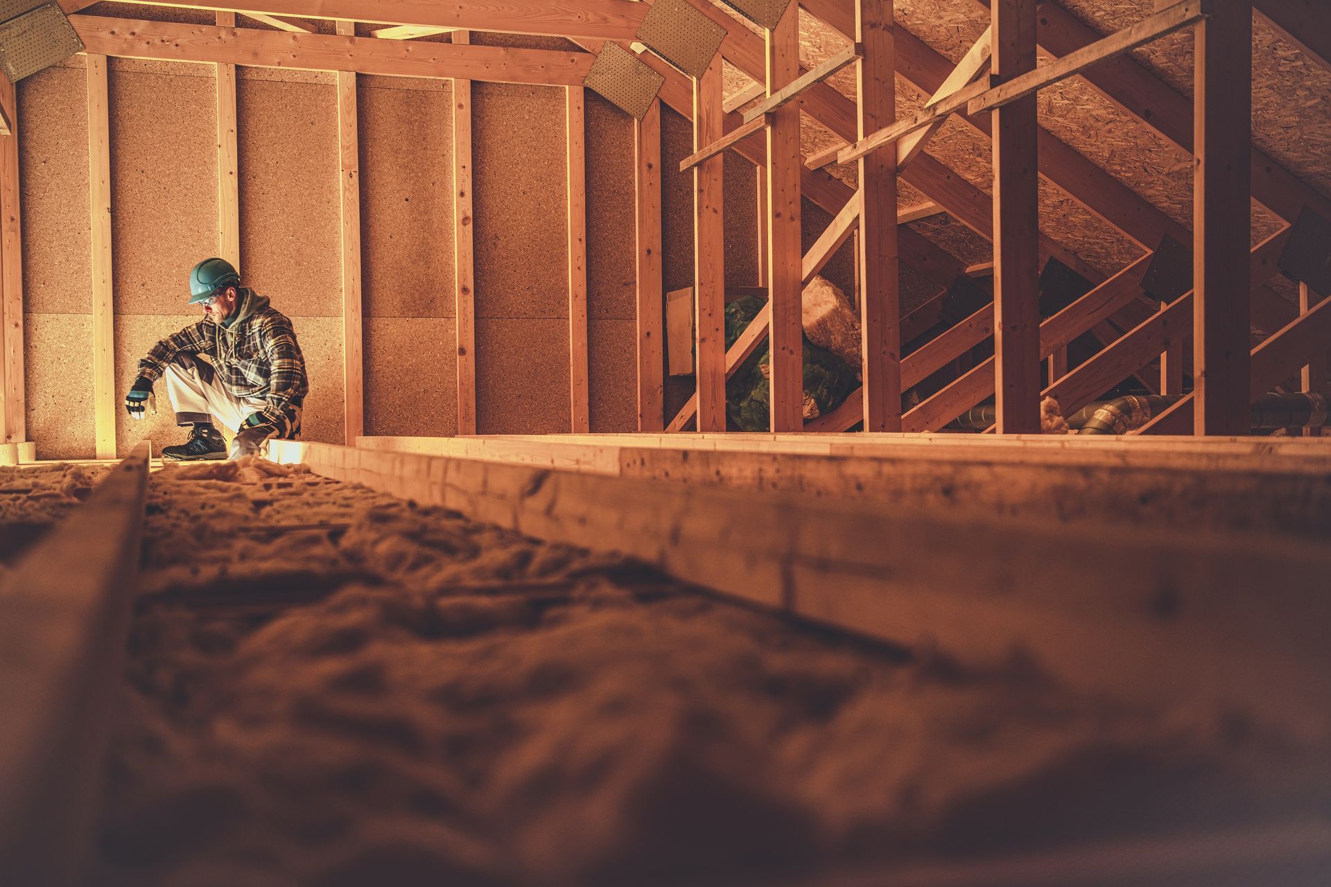 Un artisan dans des combles effectue des travaux d'isolation