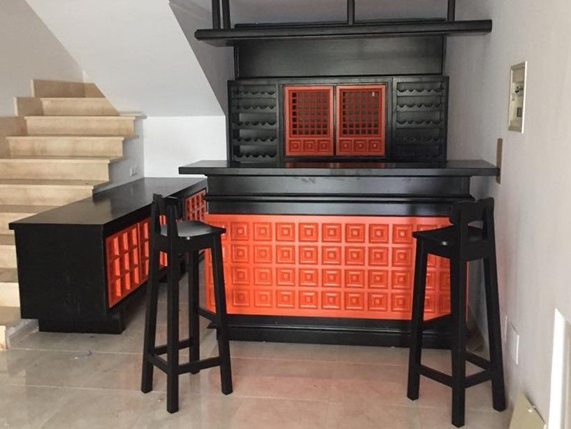 Bar negre i taronja amb tamborets al costat d'una escala.