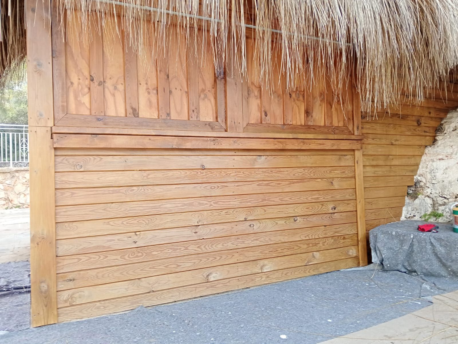 Estructura de fusta amb teulada de palla i terra de grava grisa.