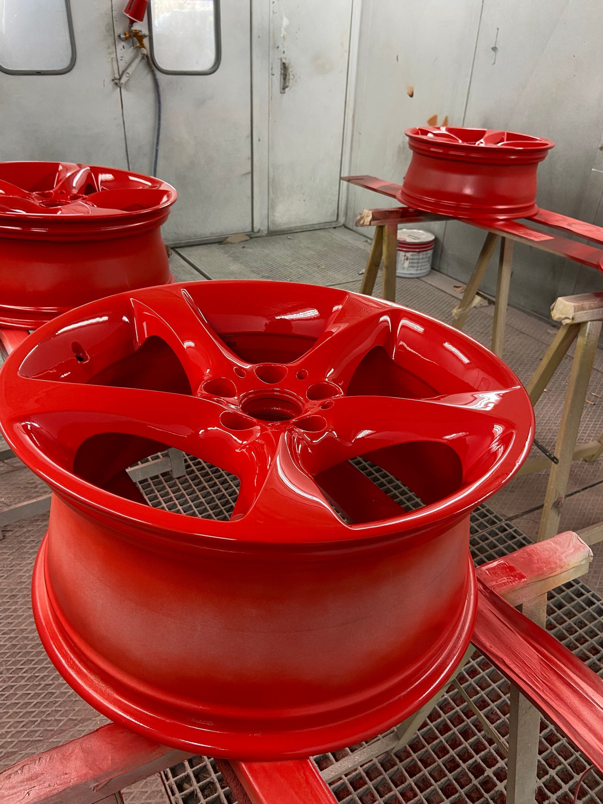 Llantes de cotxe vermelles acabades de pintar en una cabina de pintura.