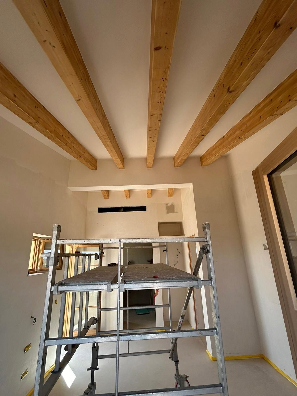 Vista interior d'una habitació amb bigues de fusta al sostre i bastides.