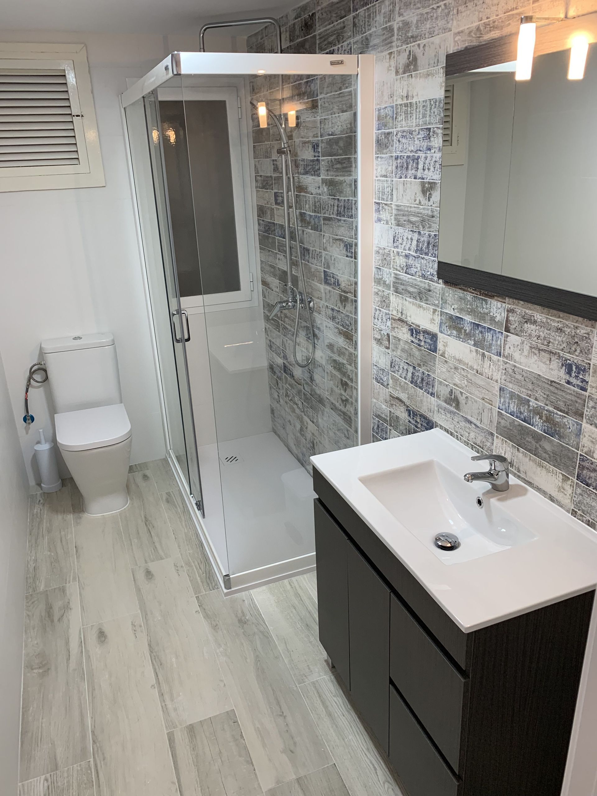 Un baño con lavabo, inodoro, ducha y espejo.