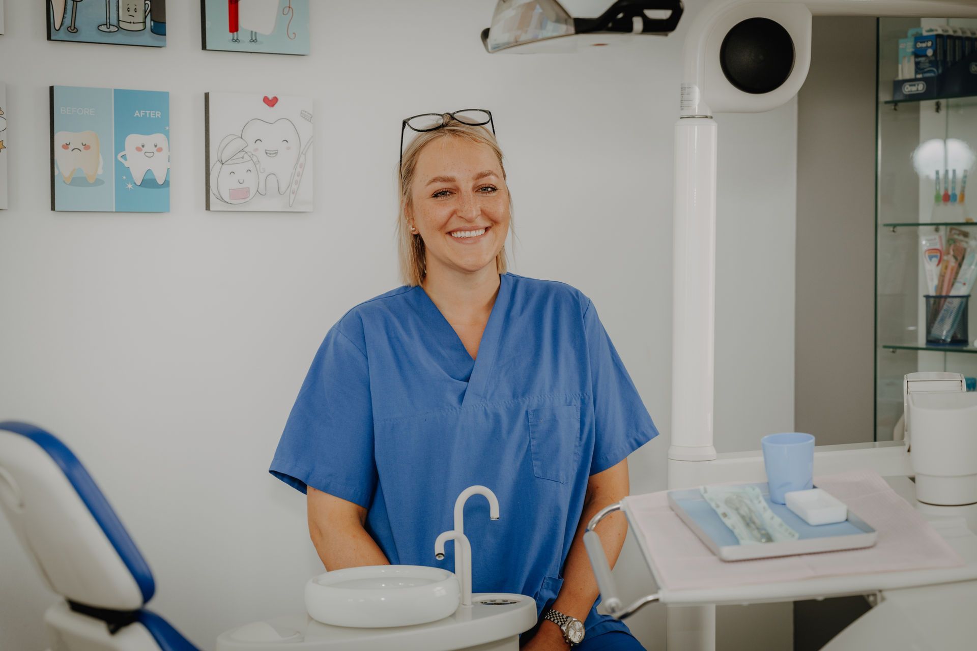 Zahnarzt in blauer OP-Kleidung lächelt in einer Zahnarztpraxis.