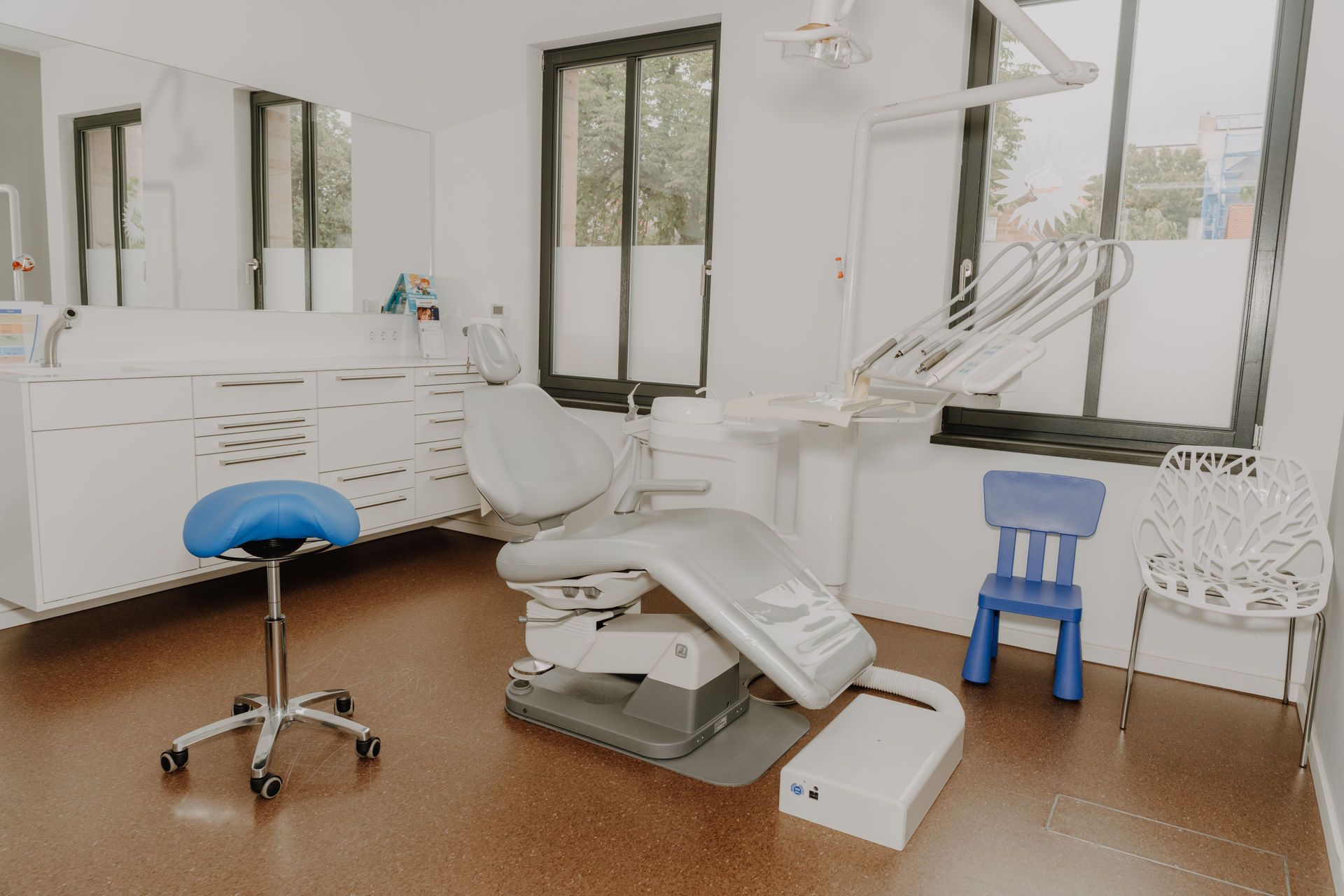 Zwei Personen in blauer OP-Kleidung halten Massagegeräte in den Händen, lächeln und sitzen.