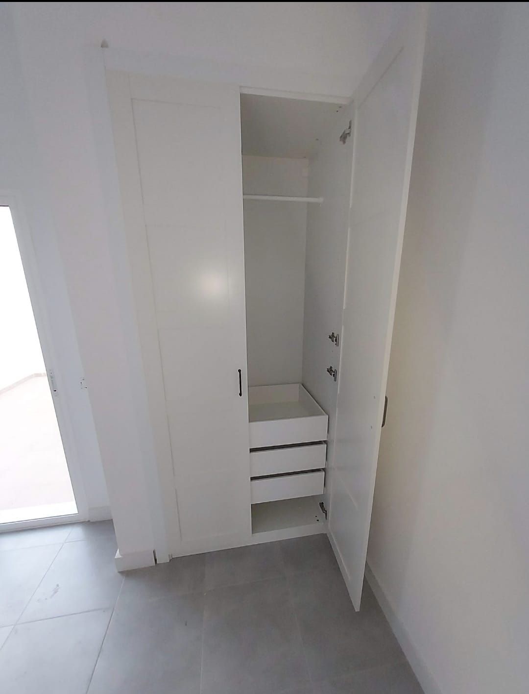 Un armario blanco con la puerta abierta y cajones.