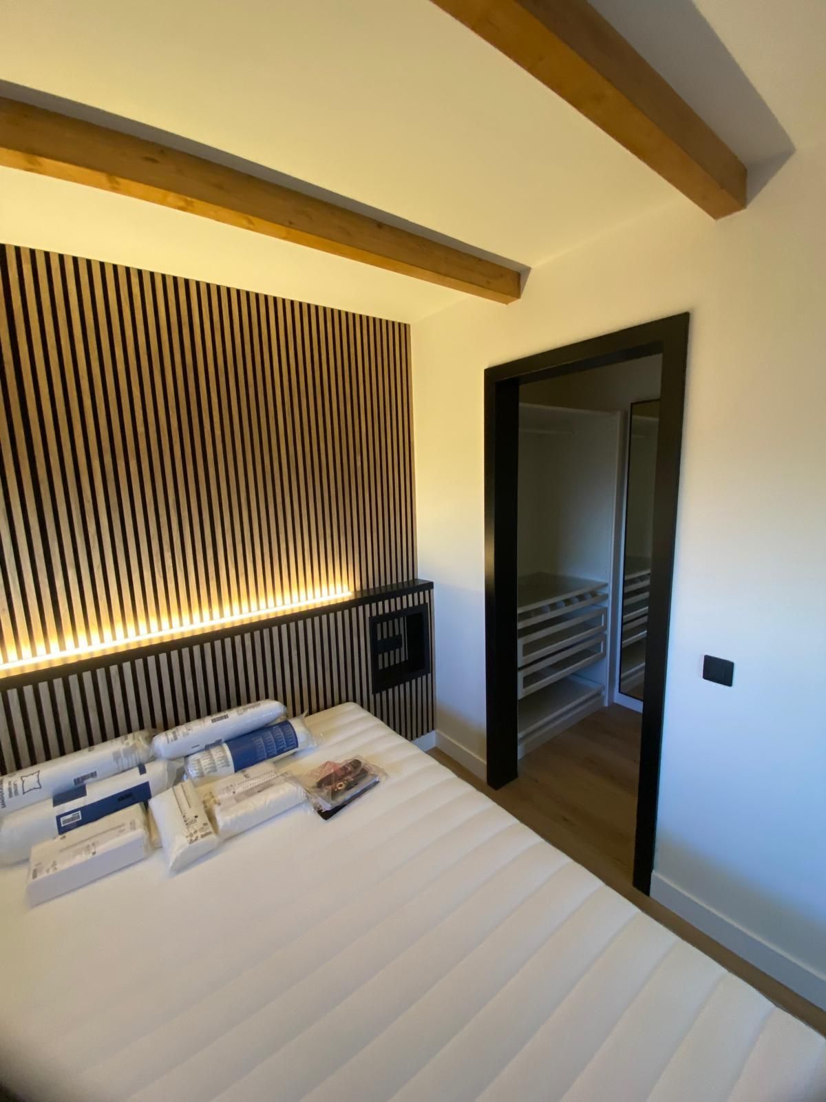Un dormitorio con una pared rayada y una cama.