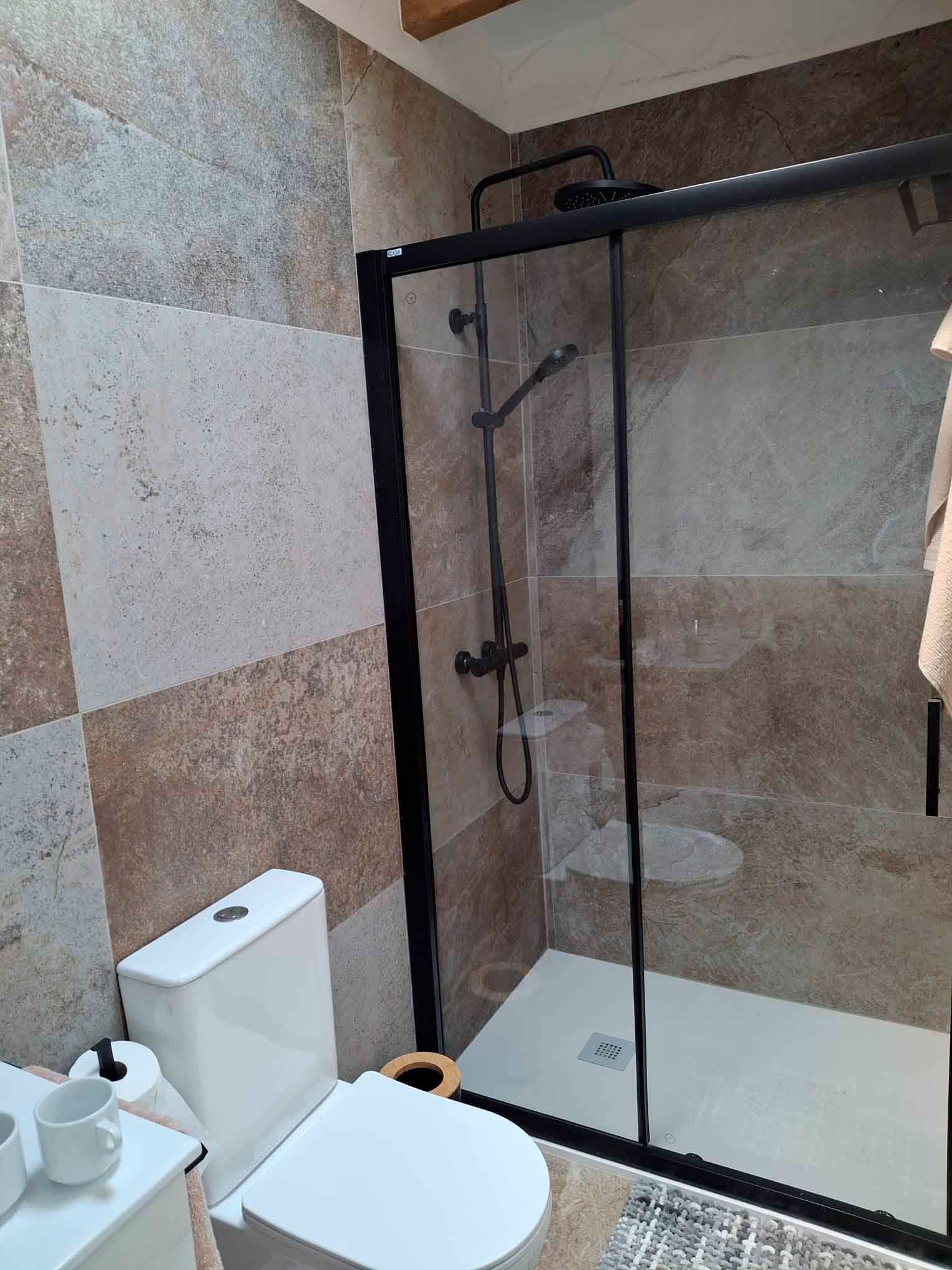 Un baño con inodoro, ducha y puerta corrediza de cristal.