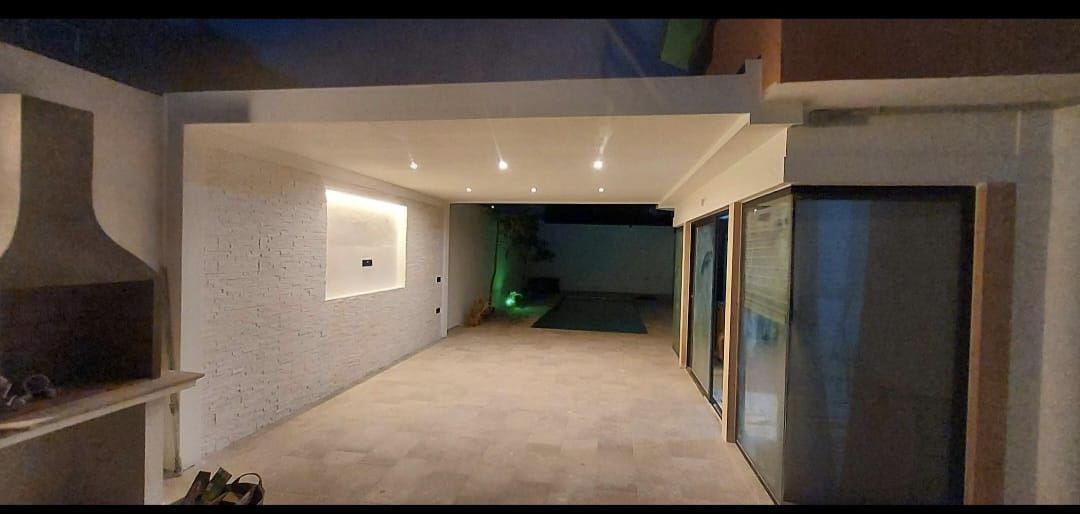 Un largo pasillo en una casa con barbacoa y piscina.