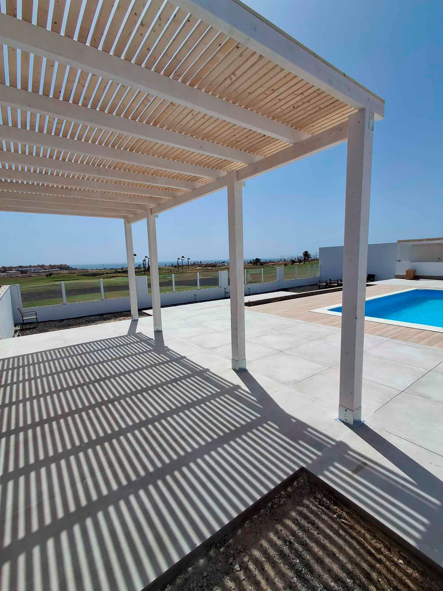 Una pérgola blanca está situada junto a una piscina.