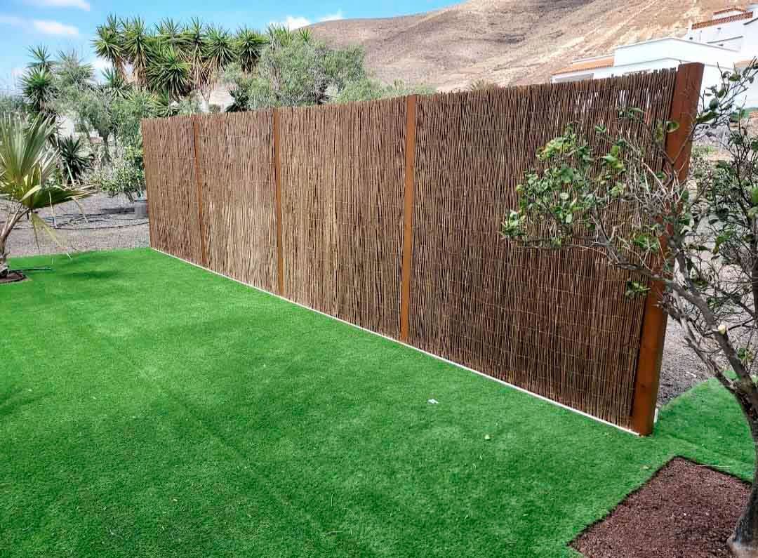 Una valla de madera rodea un exuberante césped verde en un patio trasero.