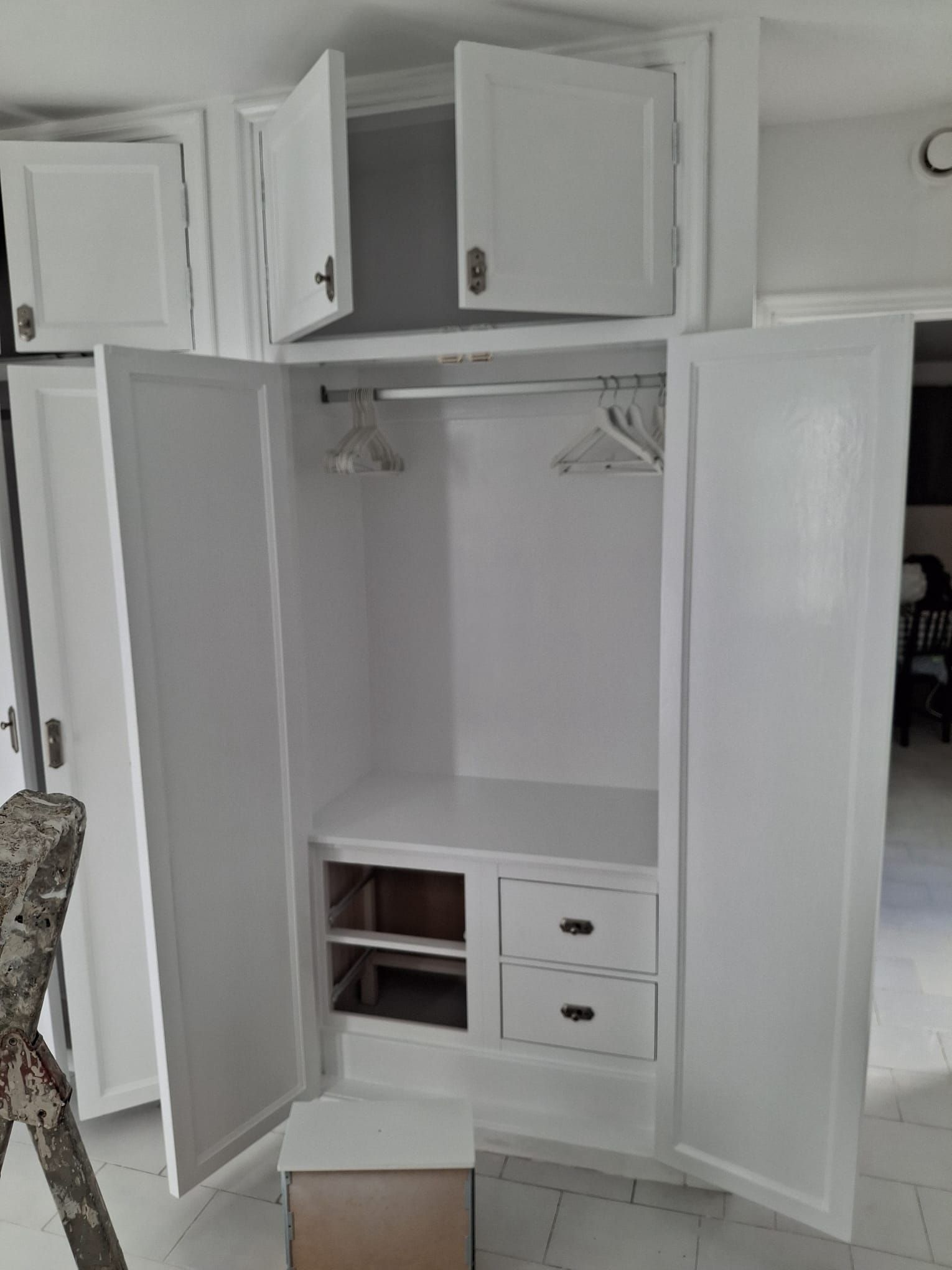 Un armario blanco con las puertas abiertas y cajones.