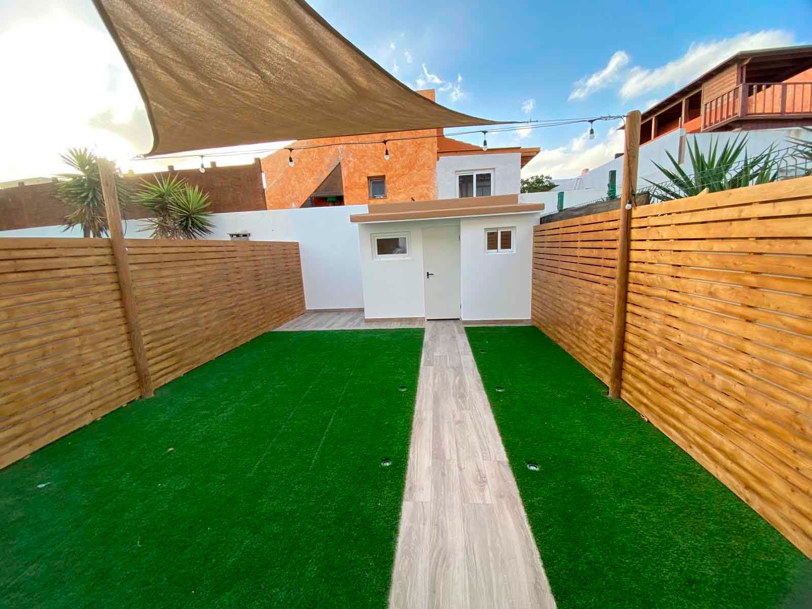 Una casa con una valla de madera y un césped delante de ella.