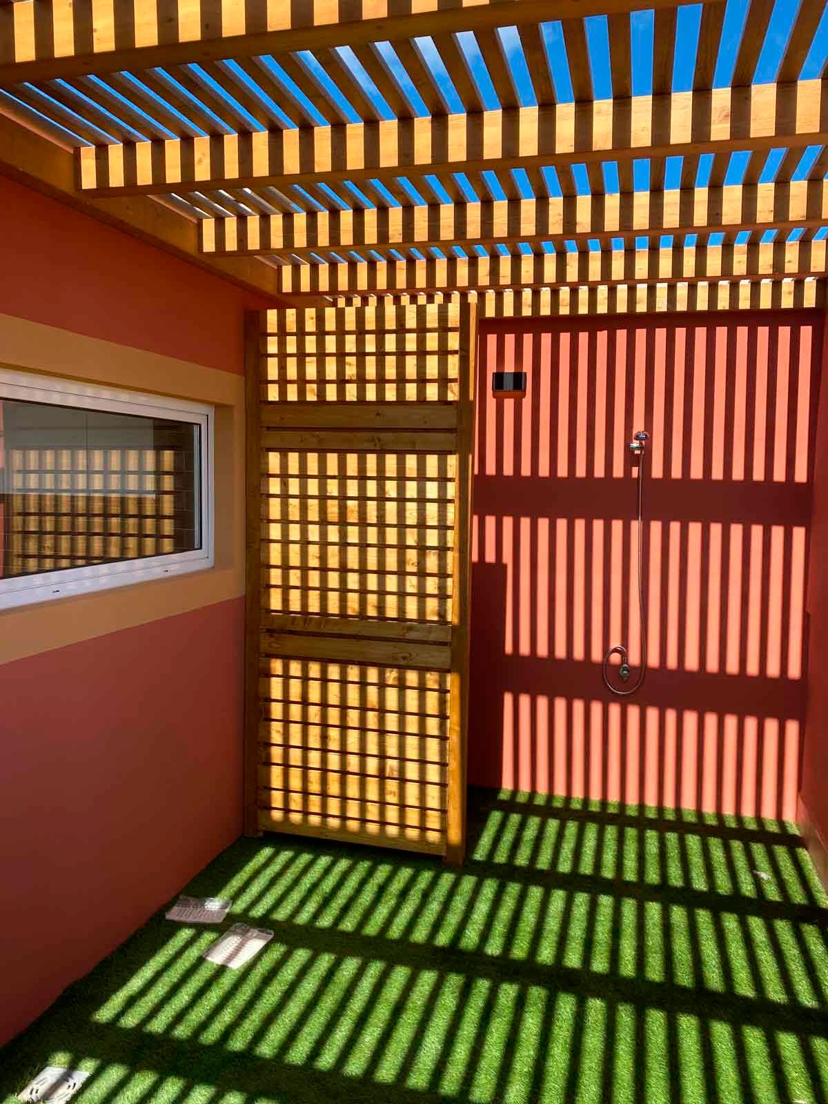 Una habitación con una pérgola y una ducha debajo.
