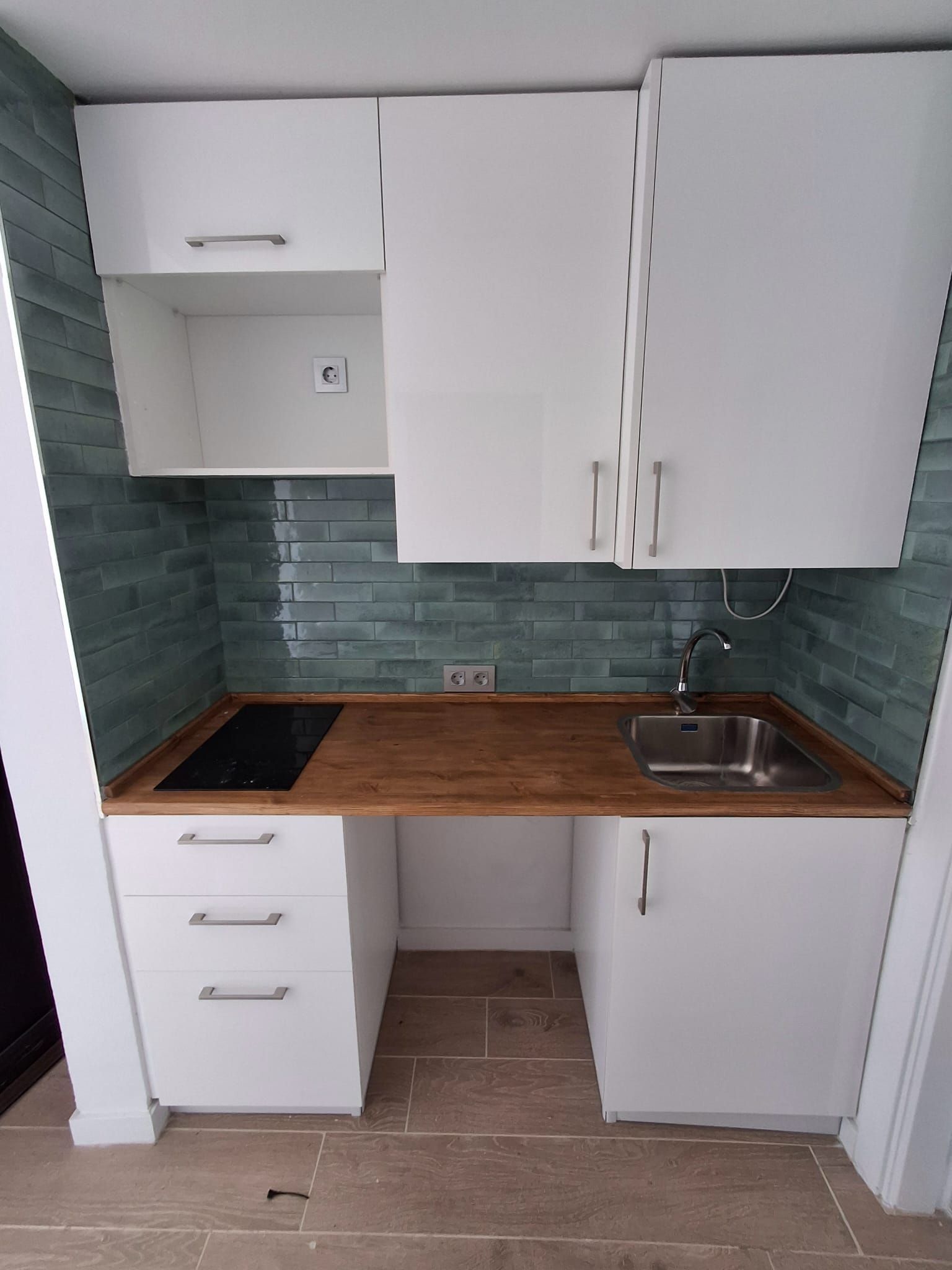 Una pequeña cocina con gabinetes blancos y un fregadero.