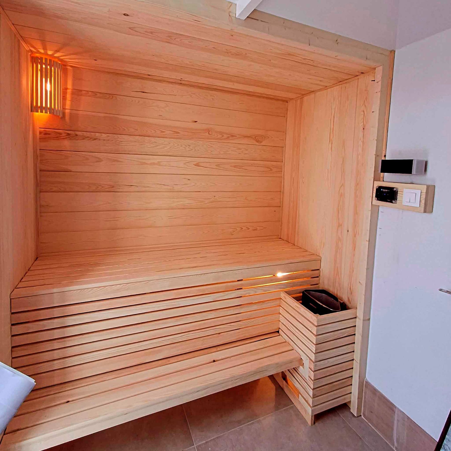 Una sauna de madera con un banco y un calentador