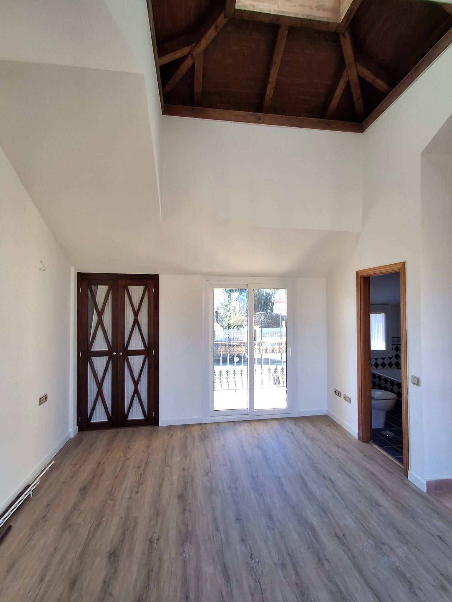 Una gran habitación vacía con pisos de madera y techo de madera.